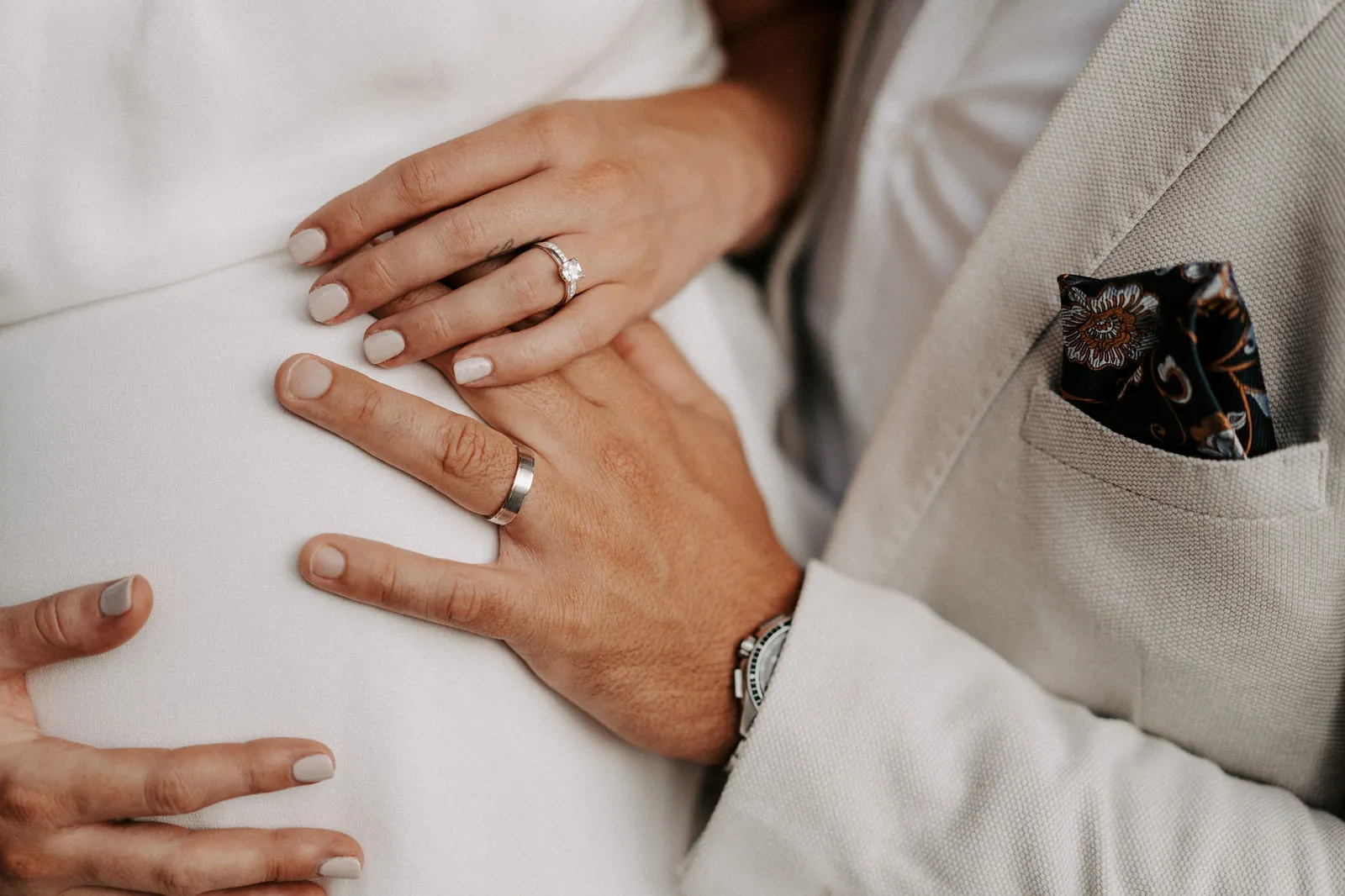 Shannon and Jacksen's hands resting together, both wedding rings in view